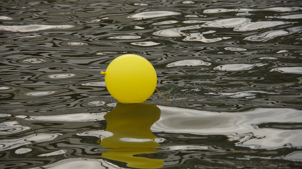 Yellow balloon with a vaguely humanoid head in the reflection.